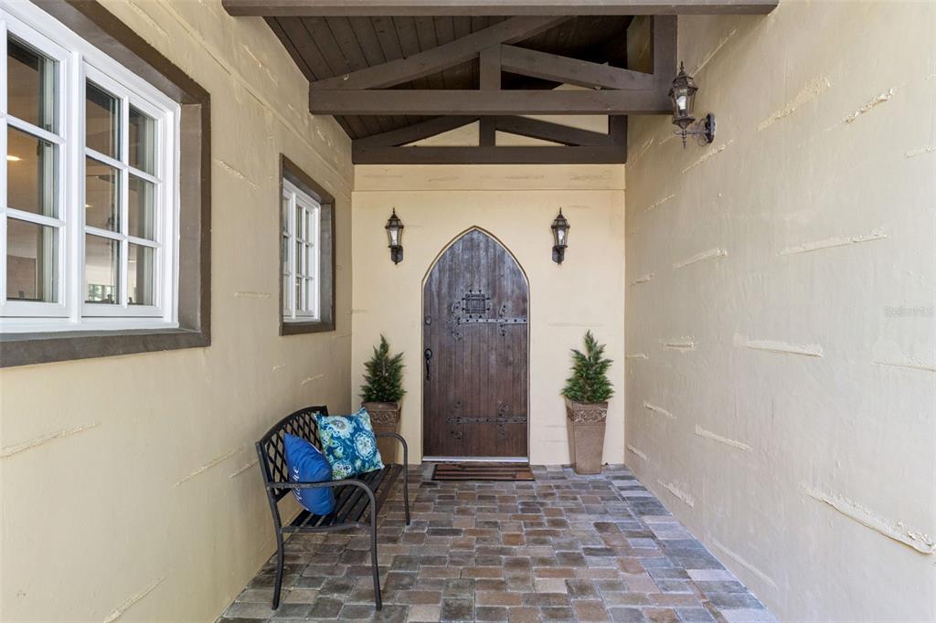 An arched wooden front door sits at the end of a covered brick entryway — 1629 HEMPEL AVENUE, WINDERMERE, FL