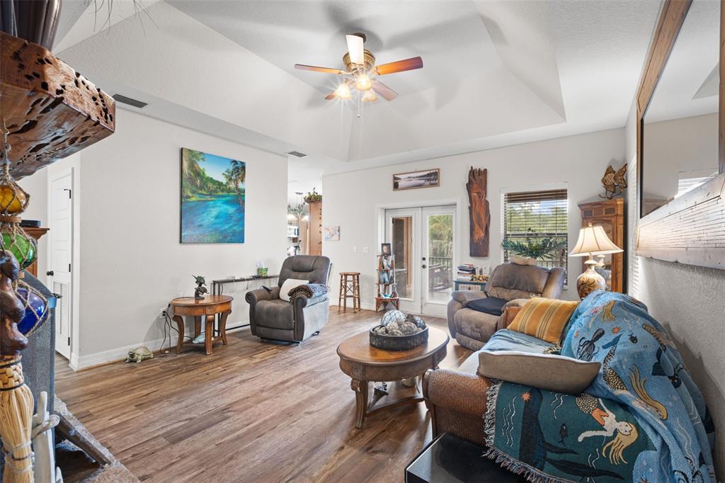 A living room with wood-look flooring, a vaulted ceiling, a ceiling fan, and two recliners — 4190 NW 153RD COURT, CHIEFLAND, FL