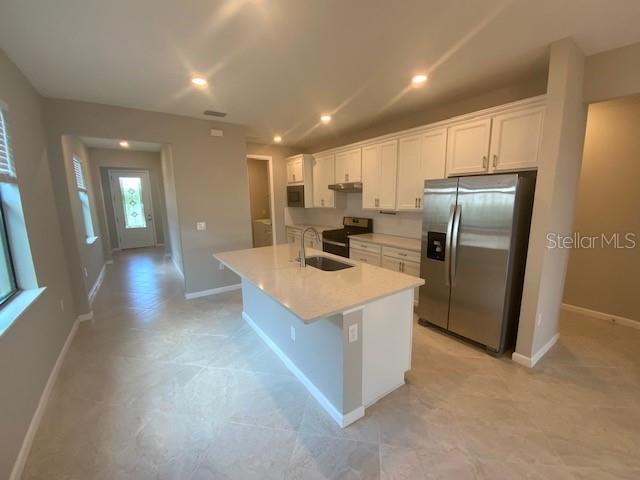 A modern kitchen features white cabinets, stainless steel appliances, and a central island with seating — 6319 CRESTED EAGLE LANE, NOKOMIS, FL