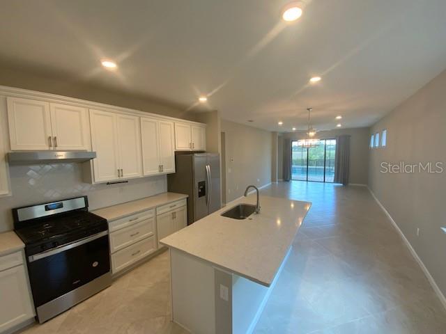 A modern kitchen features white cabinetry, stainless steel appliances, and a large central island — 6319 CRESTED EAGLE LANE, NOKOMIS, FL