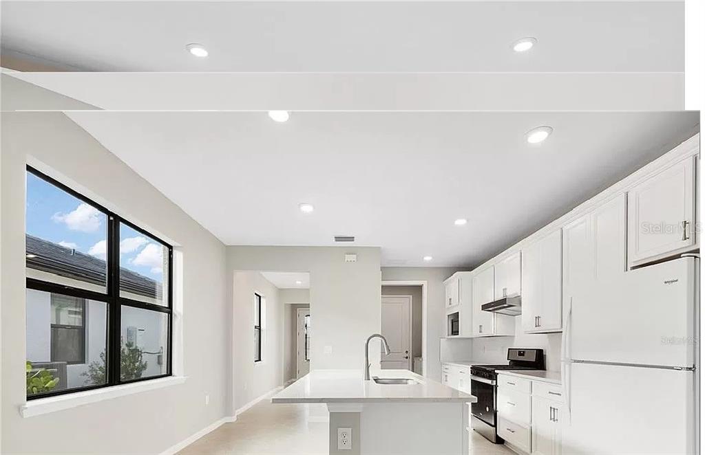 A modern kitchen features white cabinets, a central island, and recessed lighting — 6319 CRESTED EAGLE LANE, NOKOMIS, FL