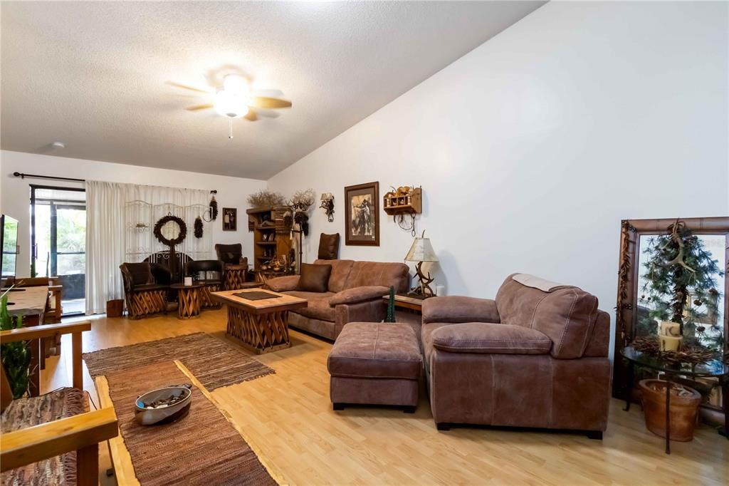 A living room features light wood flooring, rustic wooden furniture, and a vaulted ceiling — 6521 HERITAGE LANE UNIT 2621, BRADENTON, FL