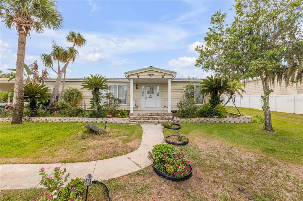 A single-story house with light siding, a covered entryway, and a landscaped front yard — 215 GARY AVENUE, OAK HILL, FL