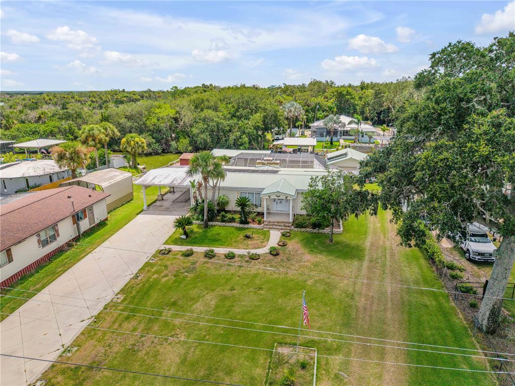 An aerial view of a single-story house with a carport, screened lanai, and large yard — 215 GARY AVENUE, OAK HILL, FL