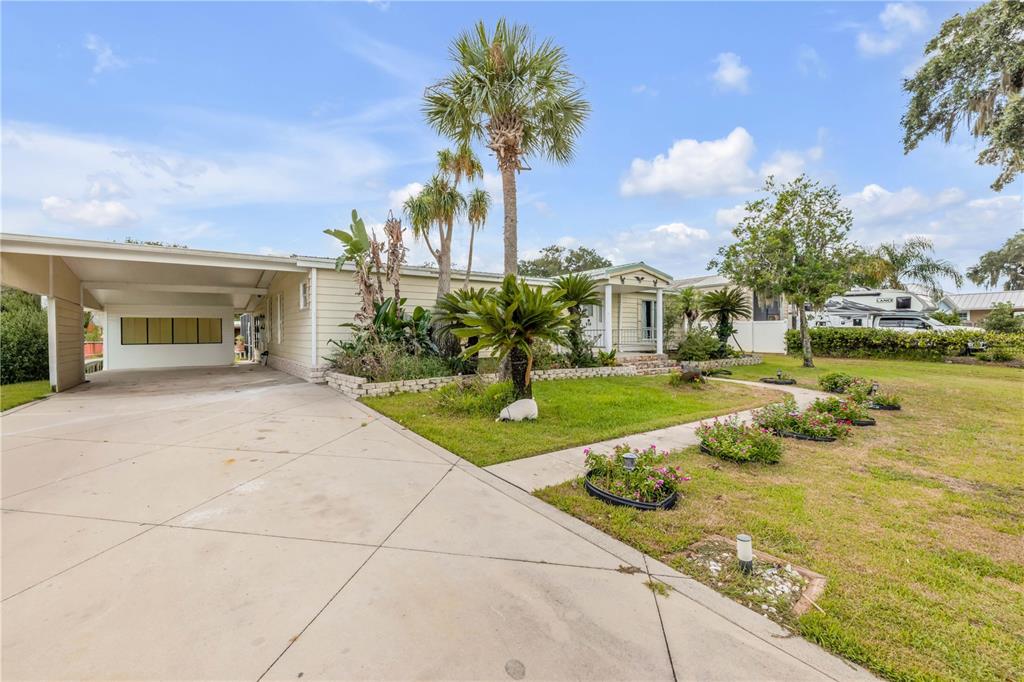 A single-story house with a carport, a concrete driveway, and a landscaped front yard — 215 GARY AVENUE, OAK HILL, FL