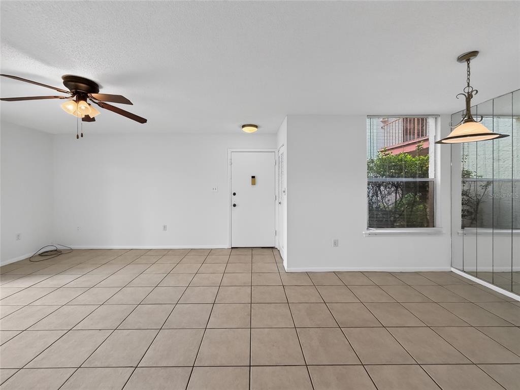 An empty room features beige tile flooring, a ceiling fan, and a white front door — 518 ORANGE DRIVE UNIT 11, ALTAMONTE SPRINGS, FL