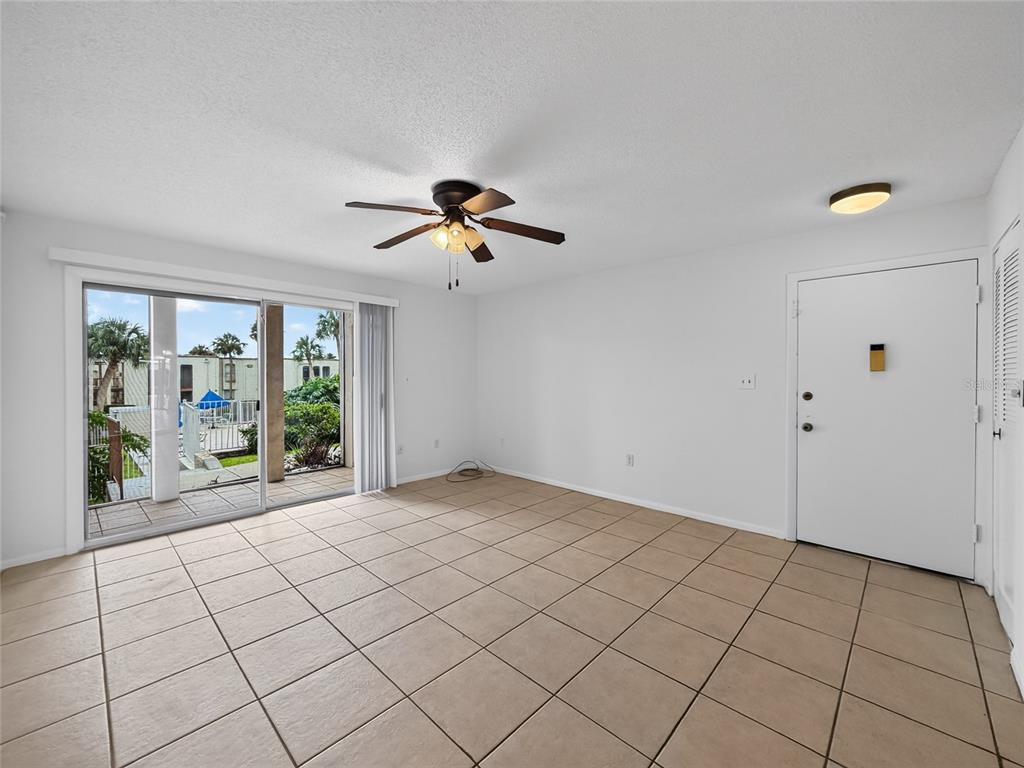 A living room with beige tile flooring, a ceiling fan, and a sliding glass door — 518 ORANGE DRIVE UNIT 11, ALTAMONTE SPRINGS, FL