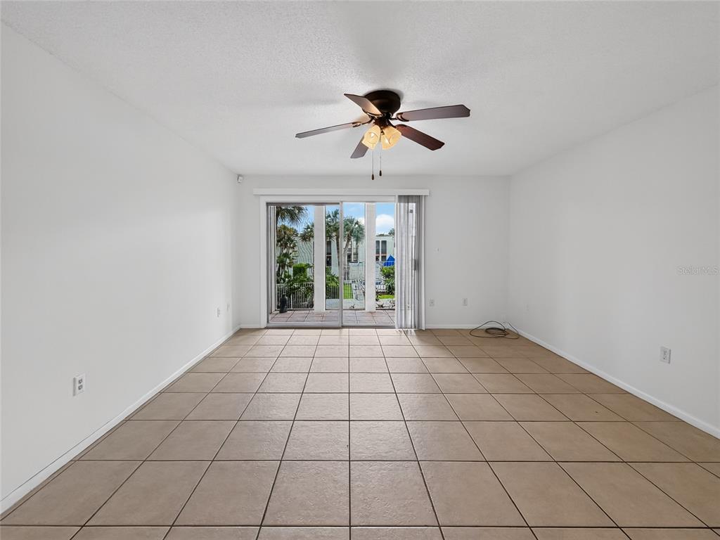 An empty room features beige tile flooring, white walls, and a ceiling fan with lights — 518 ORANGE DRIVE UNIT 11, ALTAMONTE SPRINGS, FL