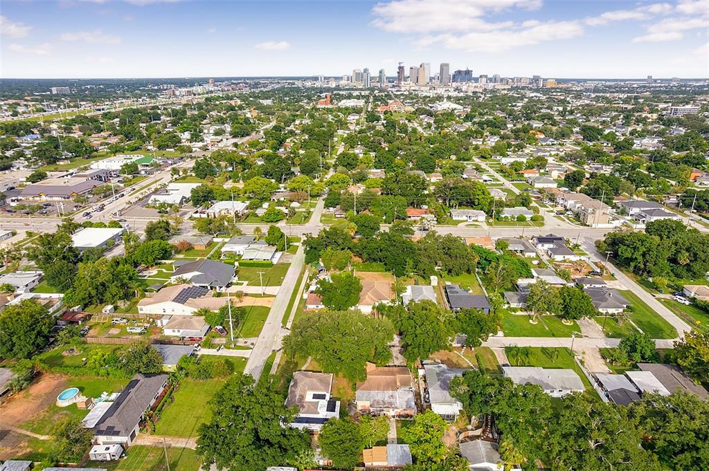 An aerial view shows a residential neighborhood with a distant city skyline under a blue sky — 612 N WOODLYNNE AVENUE, TAMPA, FL
