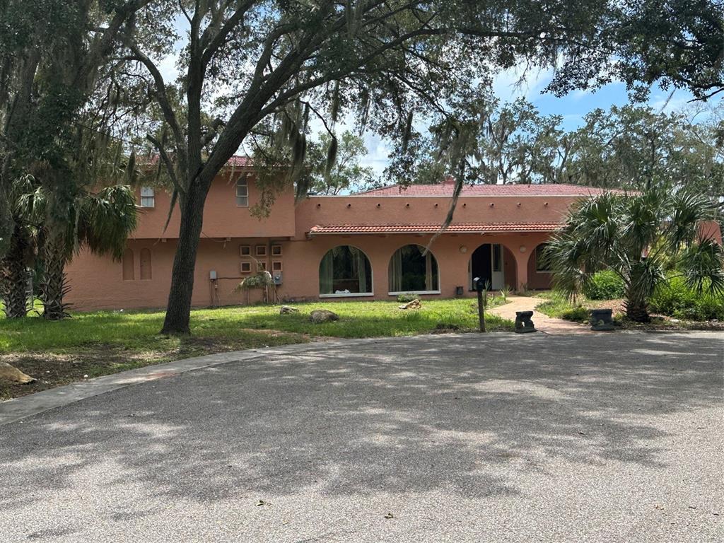 A two-story, peach-colored stucco house with arched windows and a red tile roof — 1238 FLOTILLA DRIVE, HOLIDAY, FL
