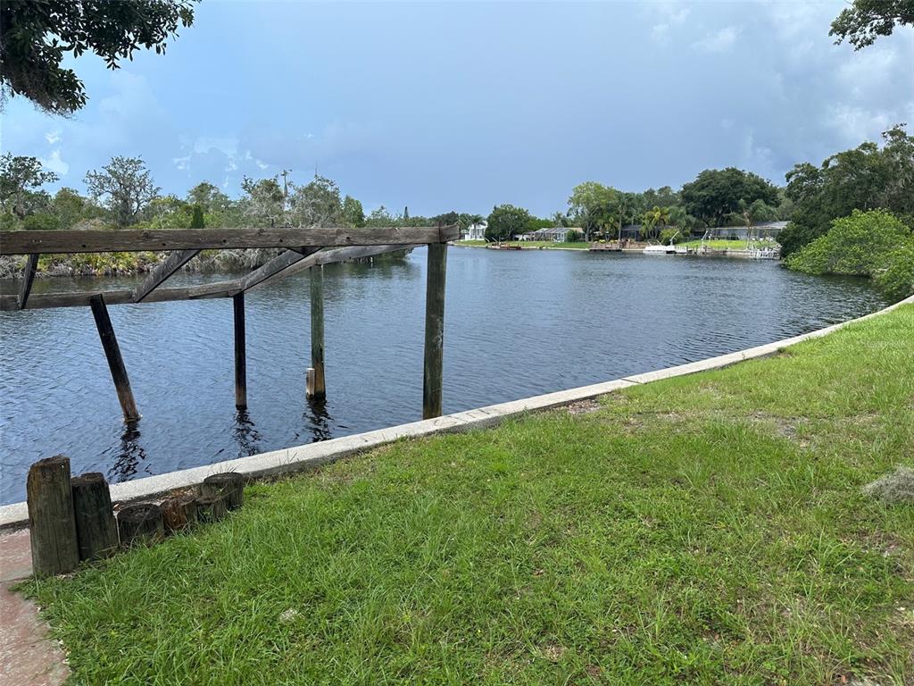 A view of a canal with a wooden boat lift frame and a grassy bank — 1238 FLOTILLA DRIVE, HOLIDAY, FL