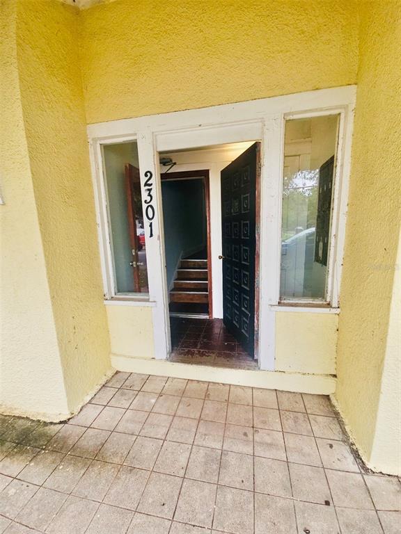 The exterior entrance features a yellow stucco wall, a tiled porch, and a glass-paneled door — 2301 N JEFFERSON STREET Apt 3, TAMPA, FL