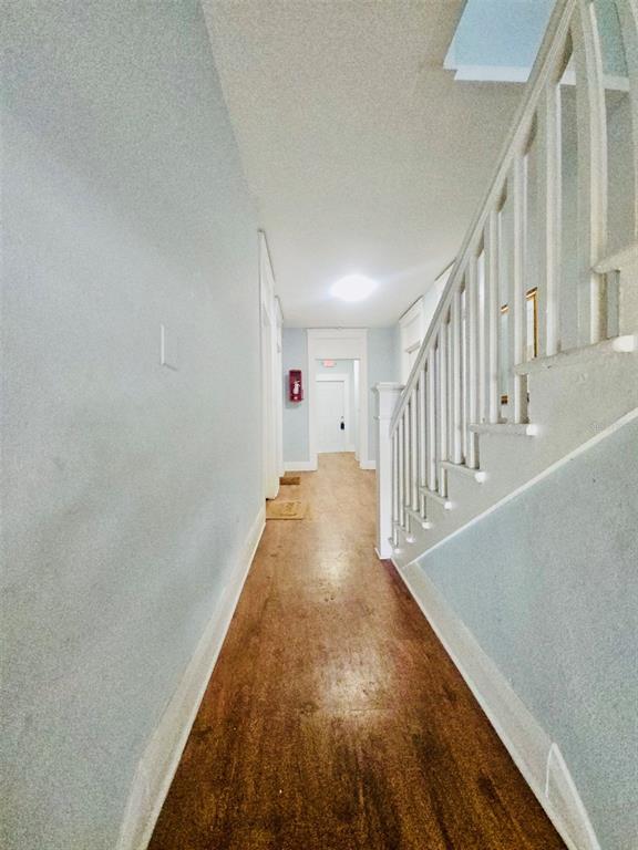 A hallway with wood flooring, light-colored walls, and a staircase with a white railing — 2301 N JEFFERSON STREET Apt 3, TAMPA, FL