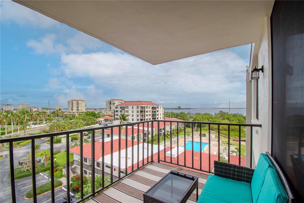 A balcony with a black metal railing overlooks a swimming pool, parking lot, and water — 6361 BAHIA DEL MAR BOULEVARD UNIT 605, ST PETERSBURG, FL