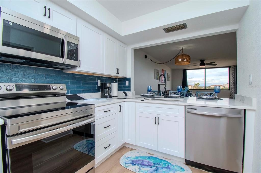 A kitchen features white cabinets, stainless steel appliances, and a blue subway tile backsplash — 6361 BAHIA DEL MAR BOULEVARD UNIT 605, ST PETERSBURG, FL