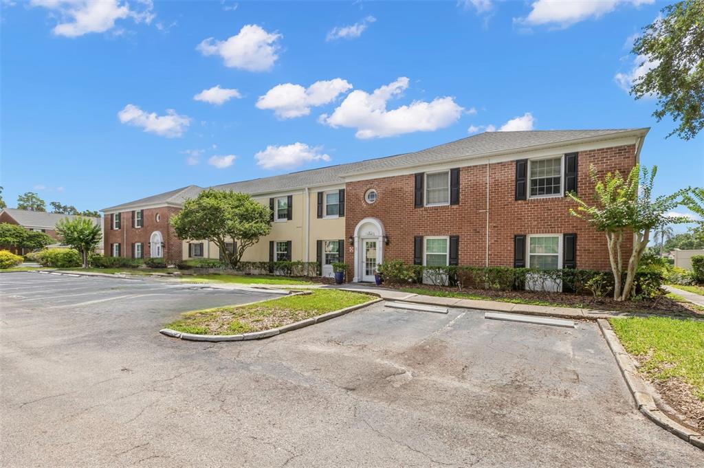 A two-story brick and stucco building exterior features a white front door with shutters — 13762 ORANGE SUNSET DRIVE UNIT 102, TAMPA, FL