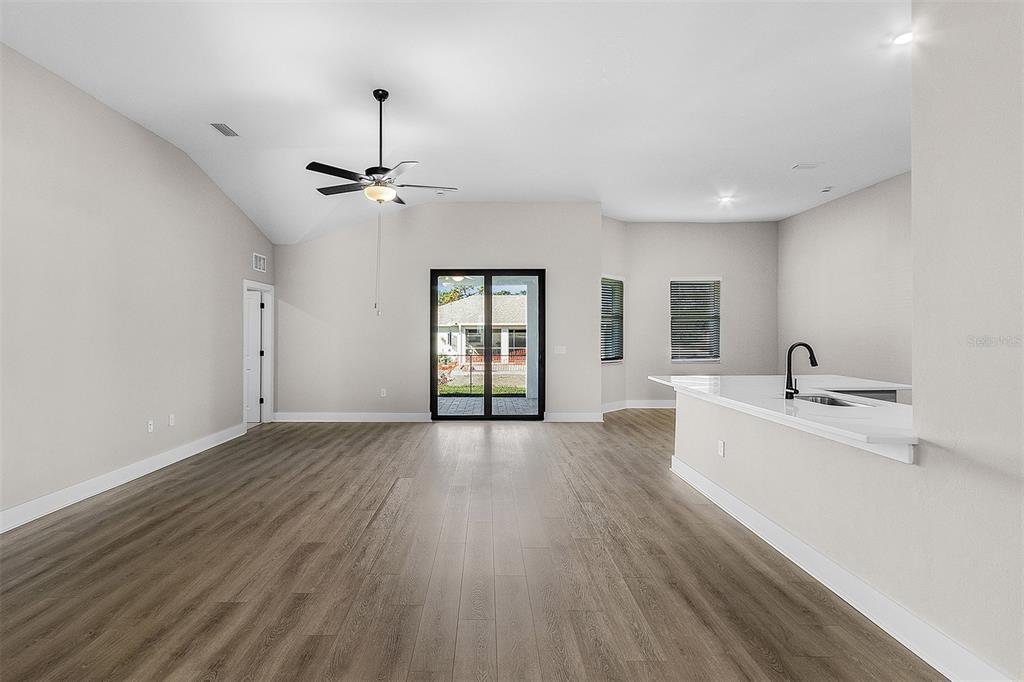 A bright, open-concept living area with wood-look flooring, a ceiling fan, and a kitchen island — 13432 LAKE GALLAGHER DRIVE, DOVER, FL
