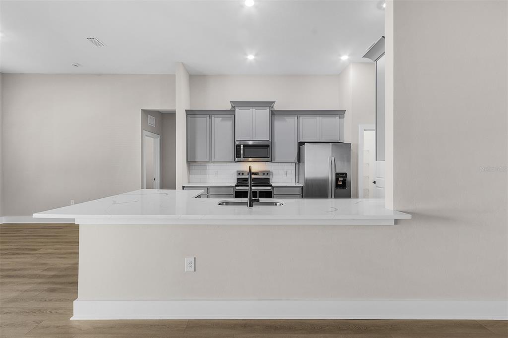 A kitchen with gray cabinets, stainless steel appliances, and a white quartz island countertop — 13432 LAKE GALLAGHER DRIVE, DOVER, FL