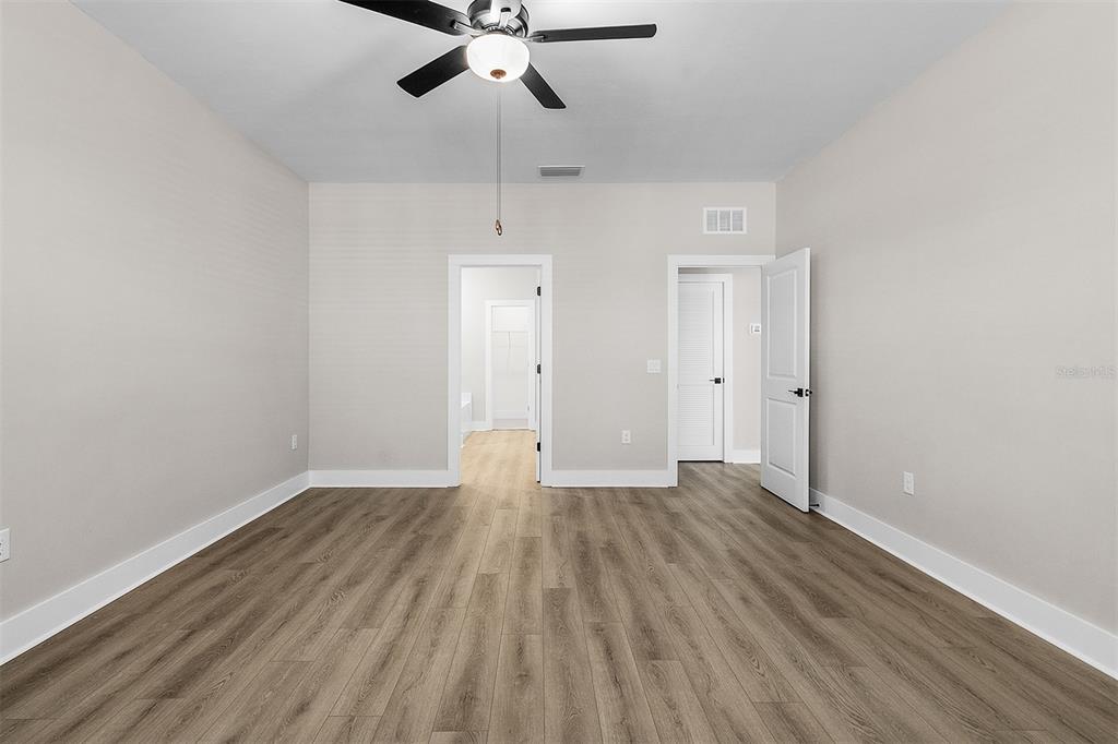 An empty bedroom with light wood-look flooring, a ceiling fan, and two doorways — 13432 LAKE GALLAGHER DRIVE, DOVER, FL