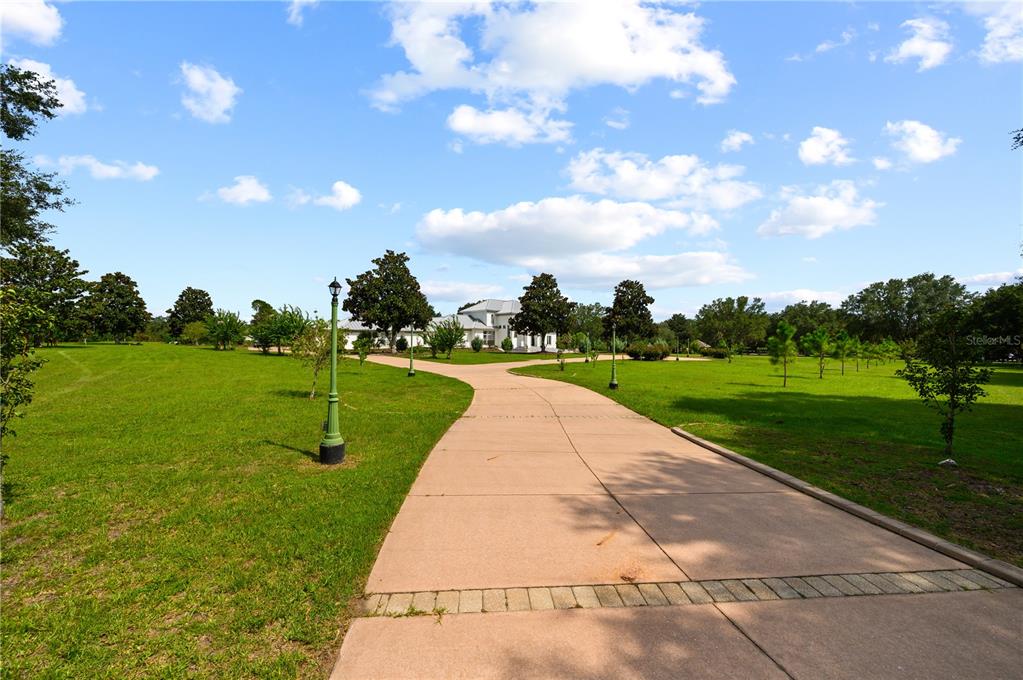 A long concrete driveway leads through a grassy lawn toward a large white house — 1515 SW 112TH STREET, GAINESVILLE, FL