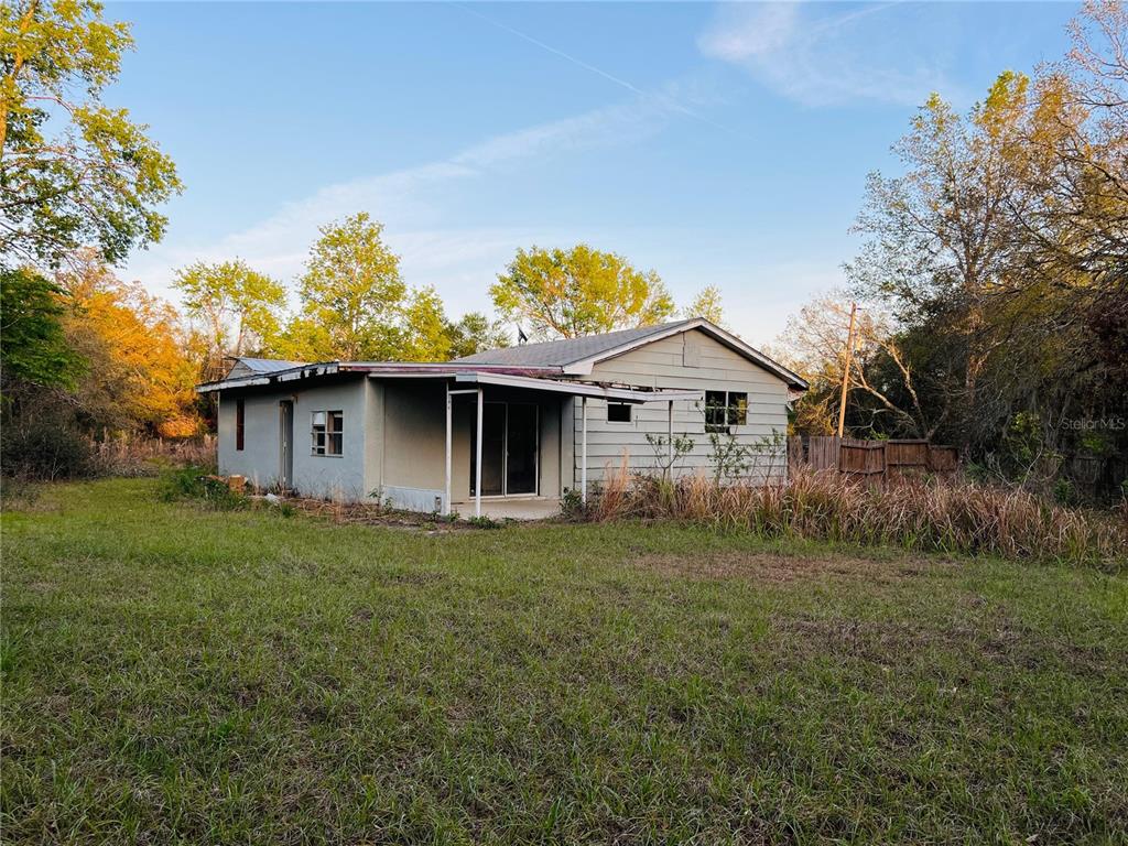 A single-story house with light-colored siding and a covered patio sits on a grassy lot — 20715 SE 141ST PLACE, UMATILLA, FL