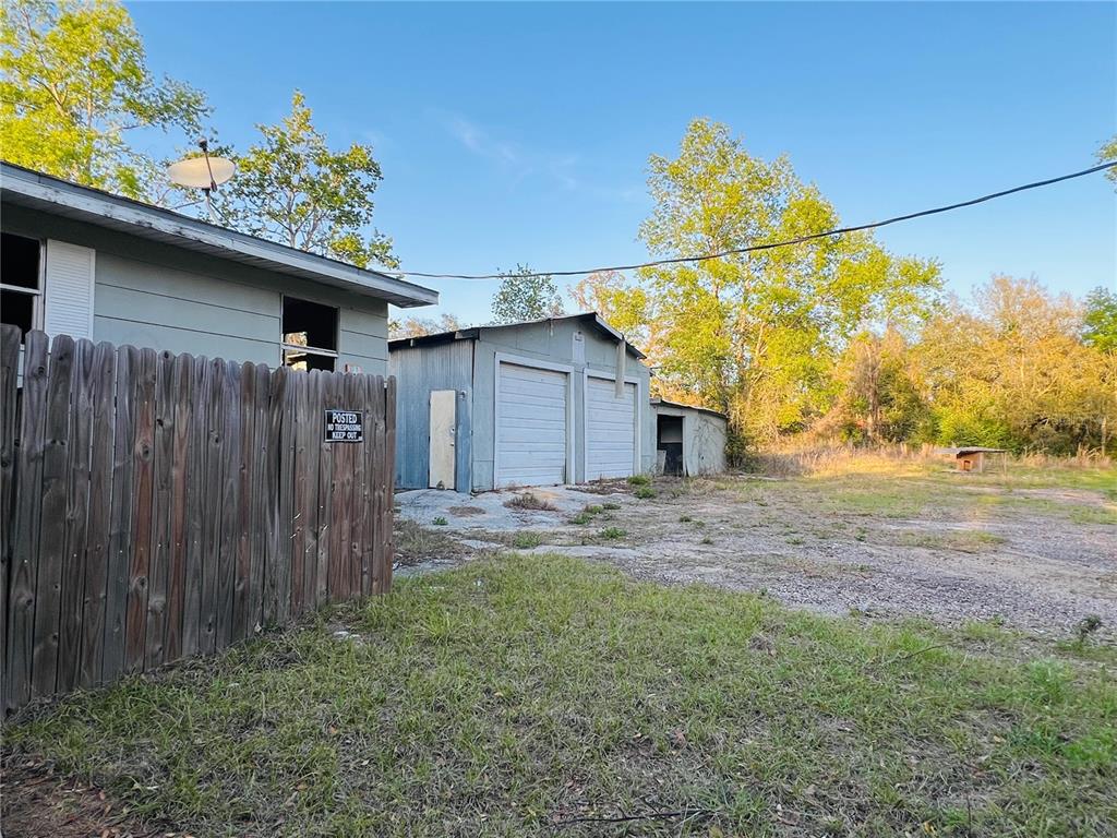 A wooden fence stands beside a house and a detached metal garage on a lot — 20715 SE 141ST PLACE, UMATILLA, FL