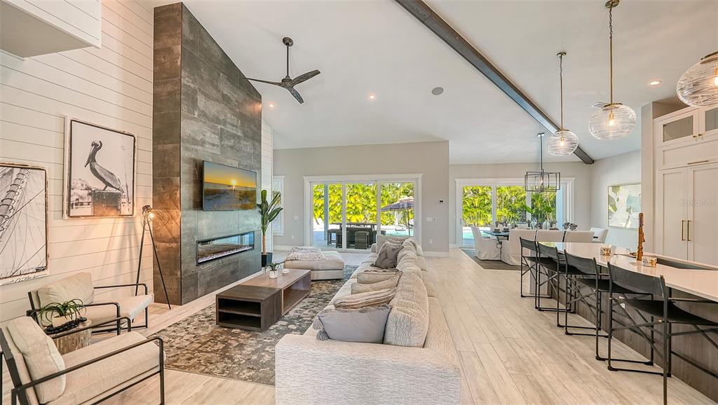 An open-concept living room features a stone fireplace, vaulted ceilings, and a kitchen island — 8006 20TH PLACE W, BRADENTON, FL