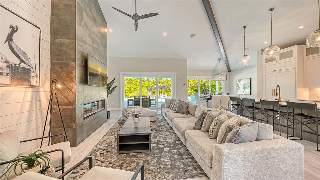 A modern living room features a stone fireplace, large sectional sofa, and open kitchen area — 8006 20TH PLACE W, BRADENTON, FL