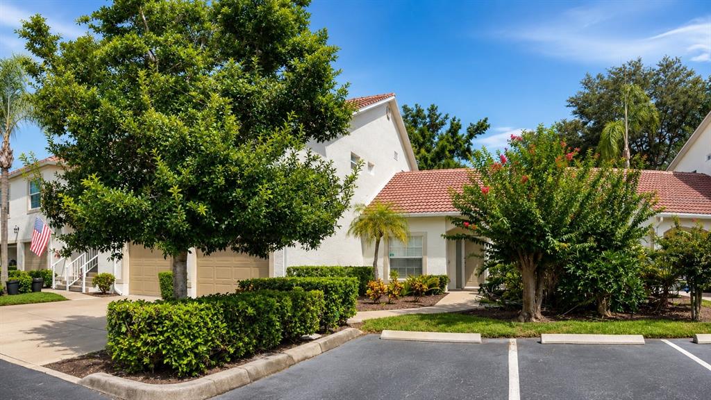 A two-story residential building with a tiled roof, garage, and landscaped front yard — 5429 STONEYBROOK LANE UNIT 102, BRADENTON, FL