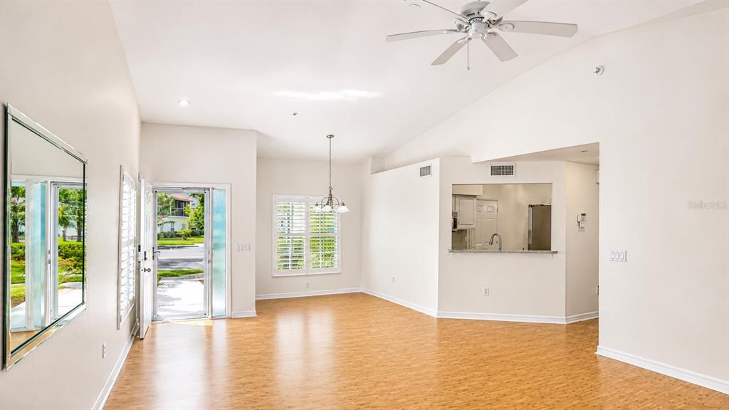 A bright living and dining area features light wood flooring, a ceiling fan, and kitchen pass-through — 5429 STONEYBROOK LANE UNIT 102, BRADENTON, FL