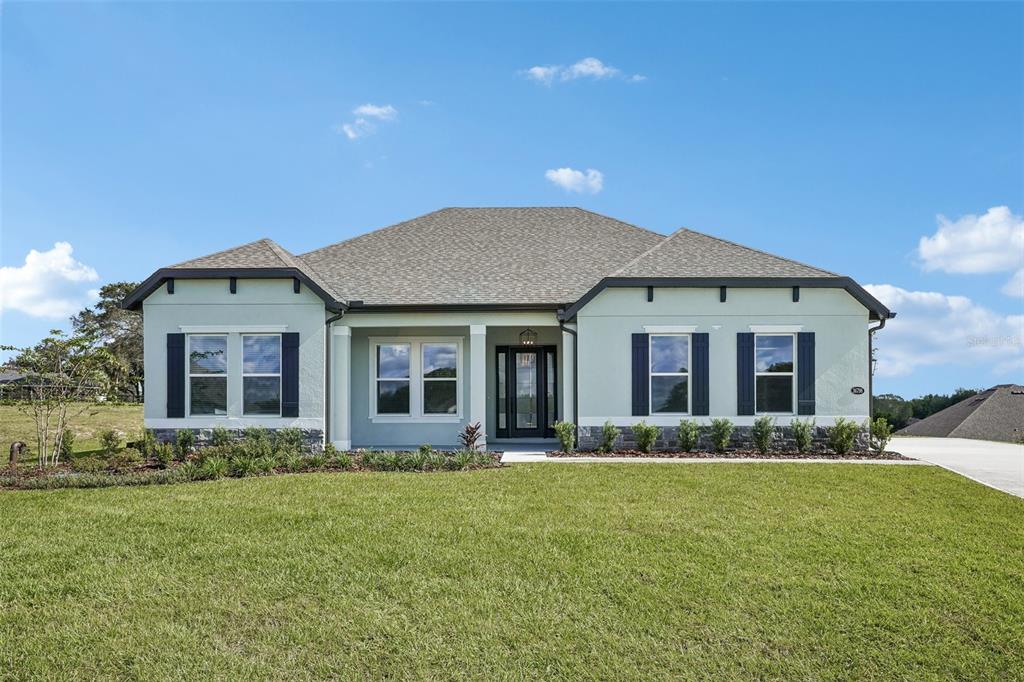 A single-story house with a white exterior, blue shutters, and a concrete driveway — 36798 SUNDOWNER TRAIL, FRUITLAND PARK, FL