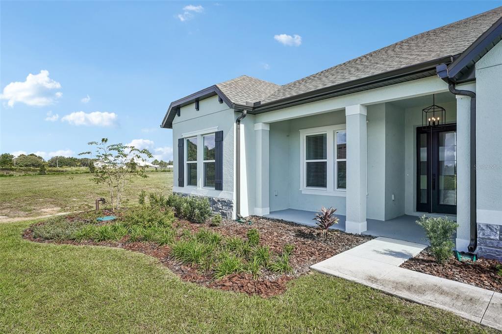 A single-story house with a concrete driveway, blue shutters, and a stone-accented exterior — 36798 SUNDOWNER TRAIL, FRUITLAND PARK, FL