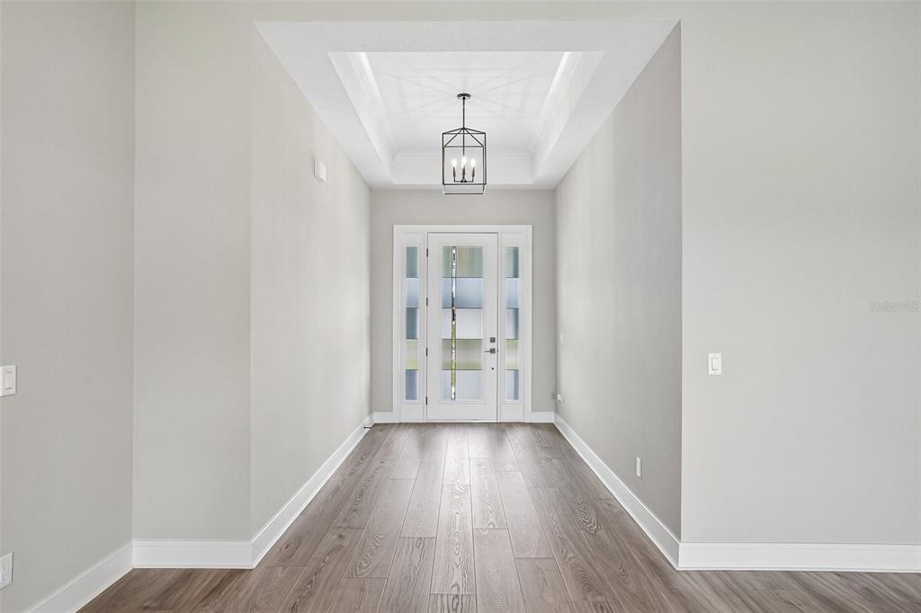 A modern kitchen features white cabinetry, a large gray island, stainless steel appliances, and light flooring — 36798 SUNDOWNER TRAIL, FRUITLAND PARK, FL
