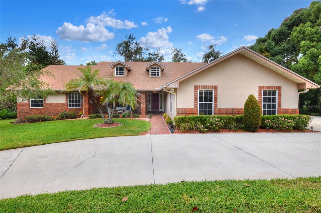 A single-story house with a brick and stucco exterior, a concrete driveway, and two dormer windows — 1221 E EDGEWOOD DRIVE, LAKELAND, FL