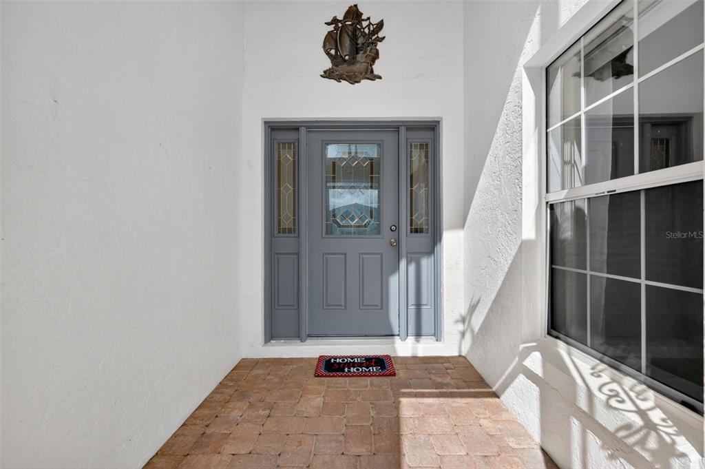 A front entryway features a gray door, a black bench, potted plants, and a rug — 17808 SE 115TH COURT, SUMMERFIELD, FL