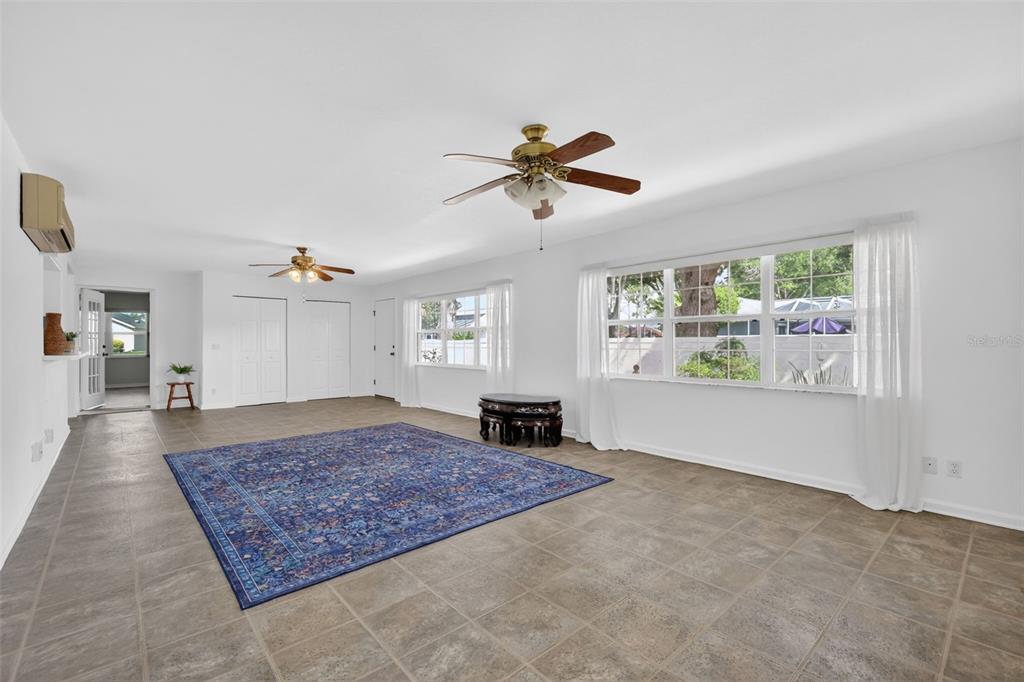 A bright living room features tile floors, two ceiling fans, and a large area rug — 17808 SE 115TH COURT, SUMMERFIELD, FL