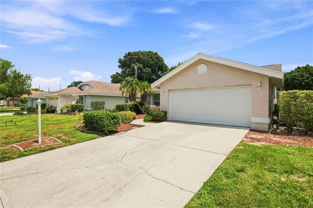 A single-story house with a white garage door, concrete driveway, and landscaped front yard — 5311 72ND STREET E, BRADENTON, FL