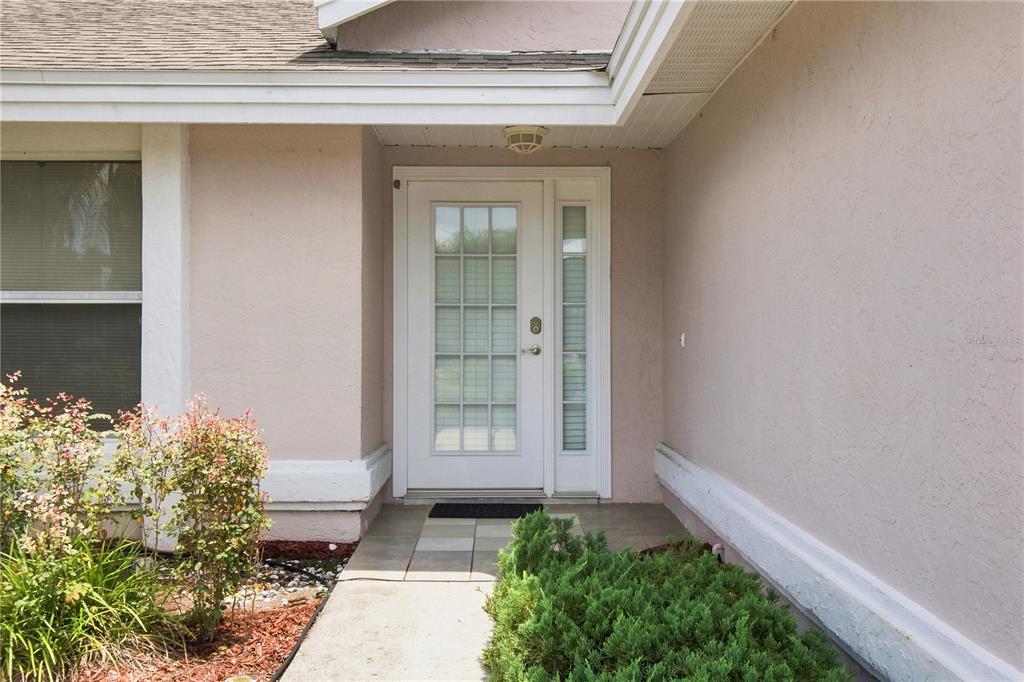 A white front door with a side light is centered on the exterior wall — 5311 72ND STREET E, BRADENTON, FL