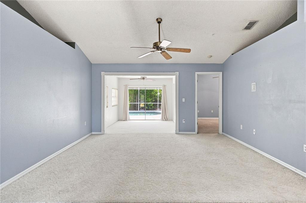 A carpeted living room with light blue walls, a vaulted ceiling, and a pool view — 5311 72ND STREET E, BRADENTON, FL