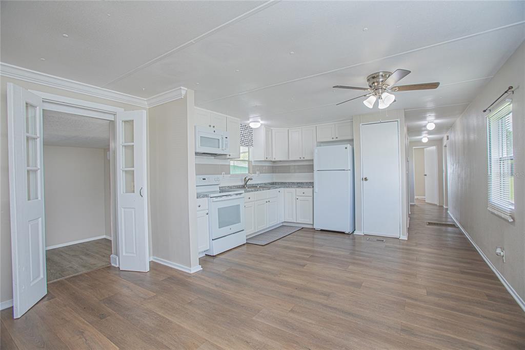 A kitchen with white cabinets, white appliances, and wood-look flooring in an open-concept space — 2009 PINE STREET, ST CLOUD, FL
