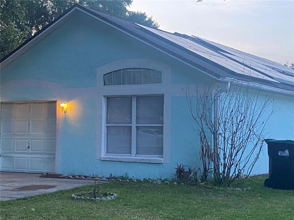 A light blue house exterior features a garage, a window with an arched transom, and solar panels — 6769 EBANS BEND, ORLANDO, FL