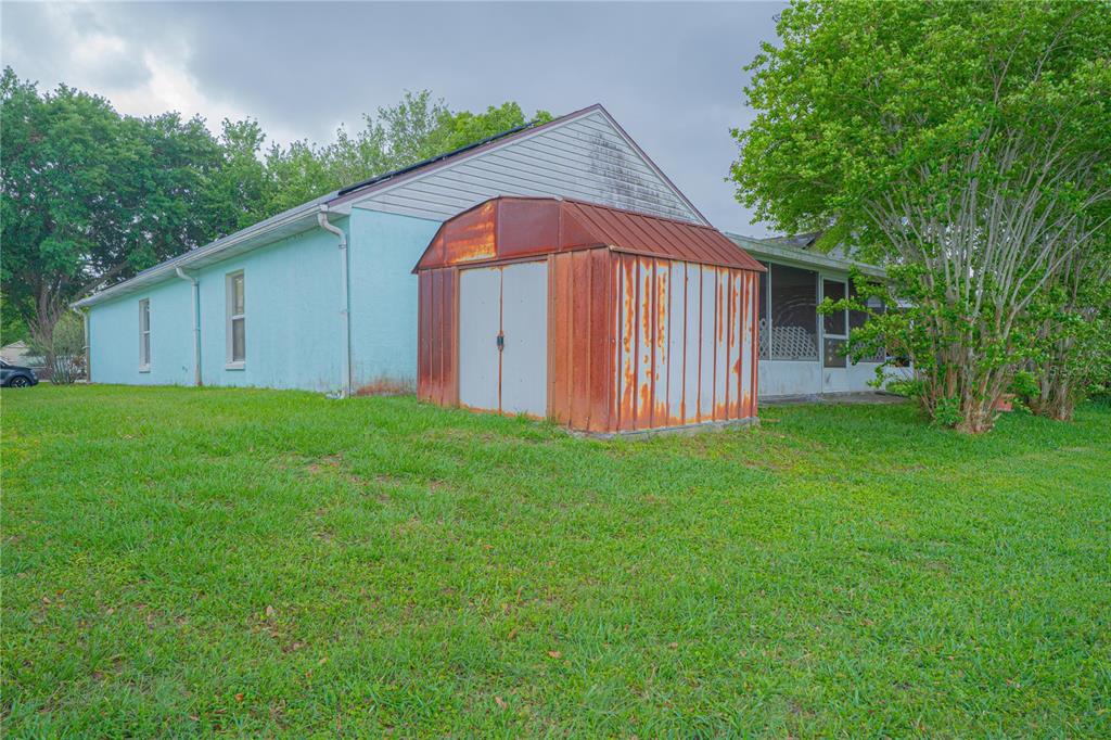 A light blue house exterior features a rusted metal shed in the backyard — 6769 EBANS BEND, ORLANDO, FL