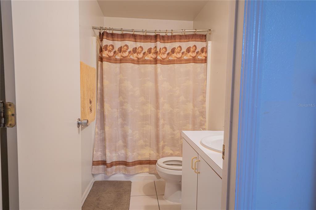 A small bathroom features a white vanity, a toilet, and a shower with a patterned curtain — 6769 EBANS BEND, ORLANDO, FL