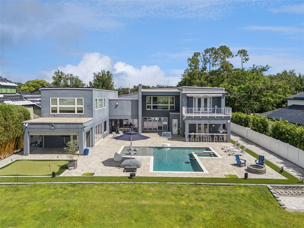 An aerial view of a modern gray house with a backyard pool and putting green — 8922 UNIVERSITY BOULEVARD, ORLANDO, FL