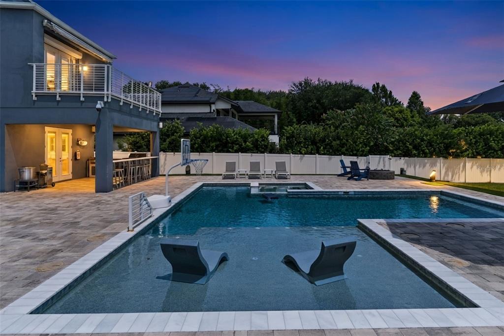 A backyard features a swimming pool with lounge chairs, a patio, and a two-story house — 8922 UNIVERSITY BOULEVARD, ORLANDO, FL