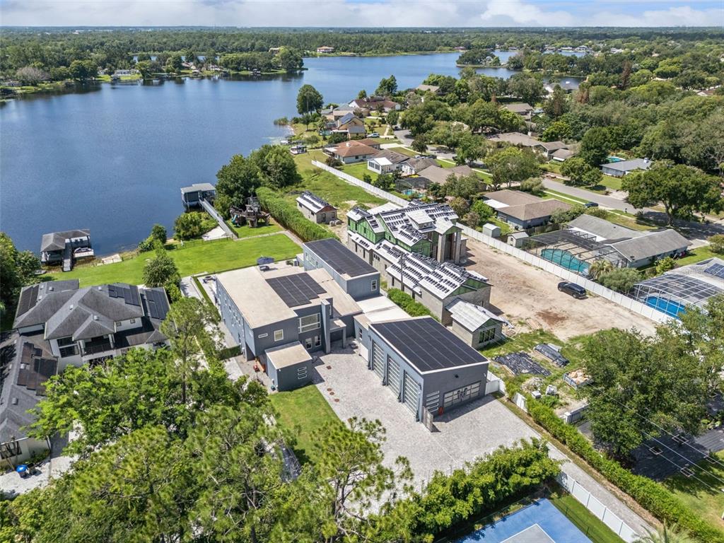 An aerial view shows a modern gray house with solar panels and a detached garage — 8922 UNIVERSITY BOULEVARD, ORLANDO, FL