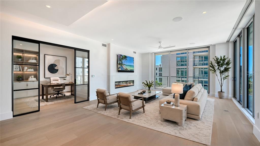A spacious, unfurnished living room features light wood flooring, floor-to-ceiling windows, and a ceiling fan — 253 GOLDEN GATE POINT UNIT 401, SARASOTA, FL