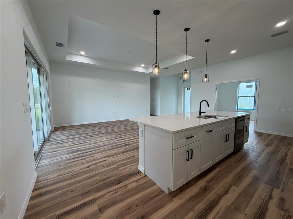 A kitchen island with white cabinets and quartz countertops sits in an open-concept living space — 4210 34TH STREET SW, LEHIGH ACRES, FL