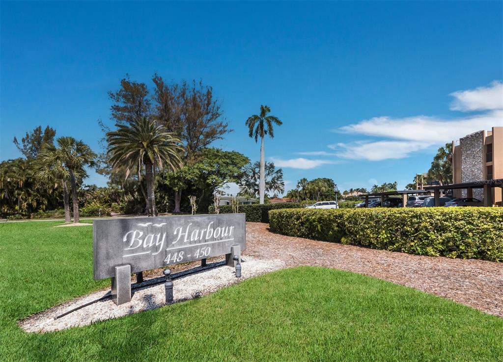 A stone sign for Bay Harbour stands on a grassy lawn near palm trees — 448 GULF OF MEXICO DRIVE UNIT A104, LONGBOAT KEY, FL