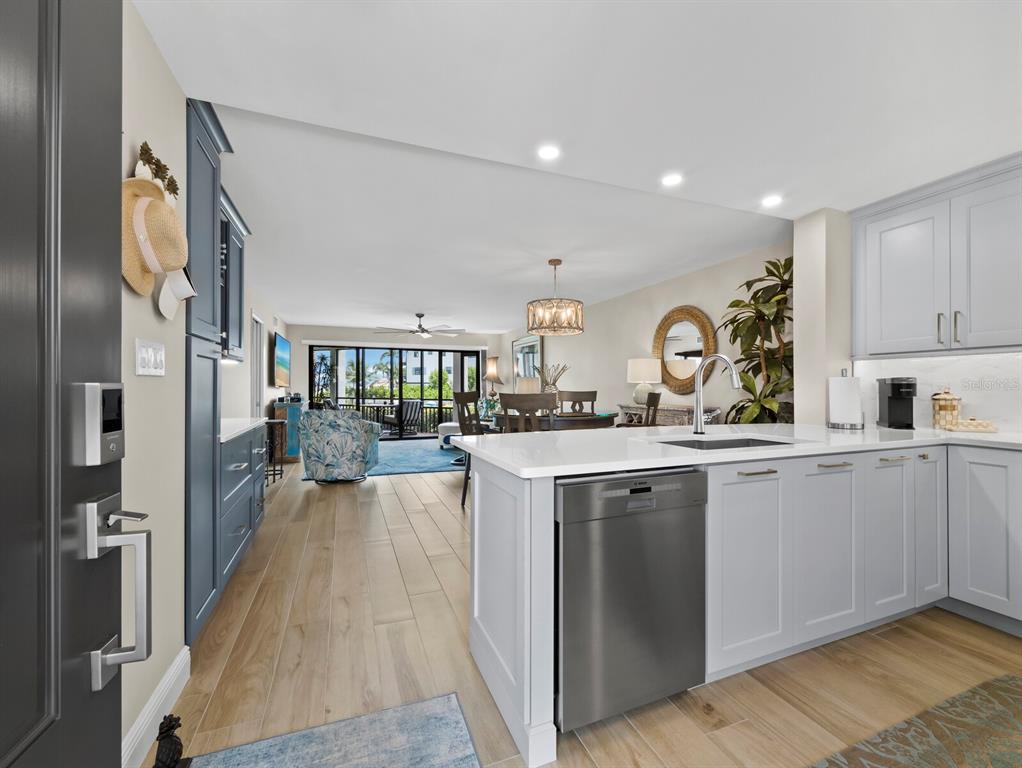 A kitchen with light gray cabinets and a stainless steel dishwasher opens to a living area — 448 GULF OF MEXICO DRIVE UNIT A104, LONGBOAT KEY, FL
